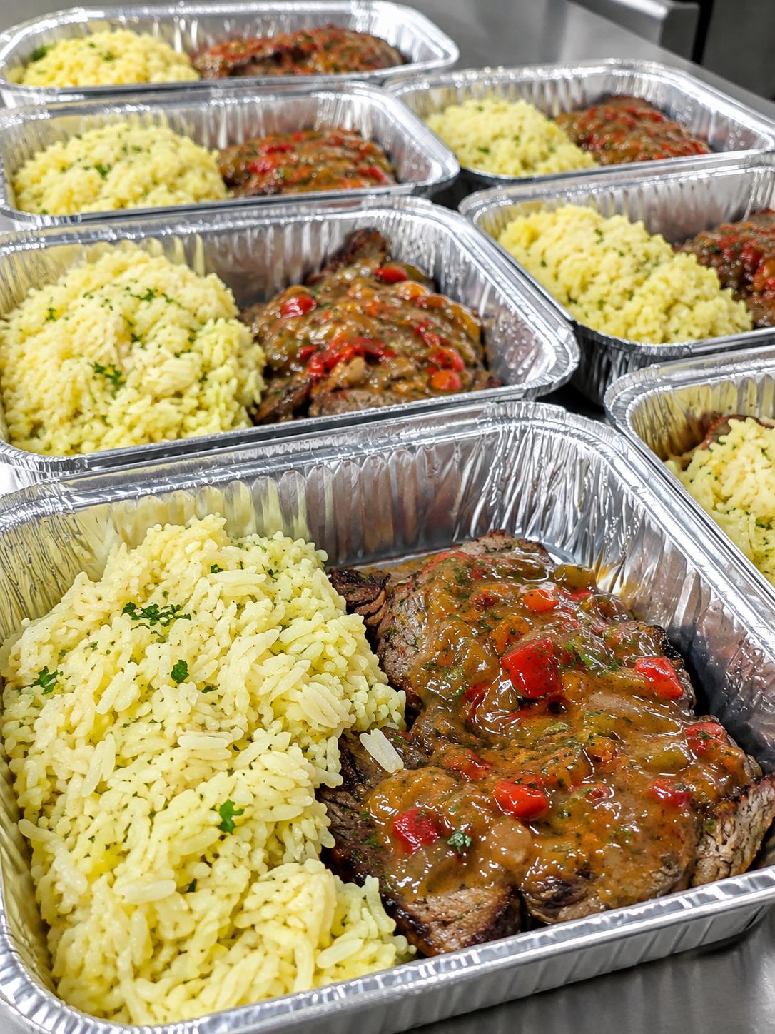 Bandejas de aluminio emplatadas en serie: arroz amarillo con perejil y carne con salsa de morrones